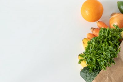 Paper bag filled with fruit and vegetables against a white background (Adobe Stock)