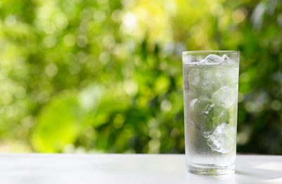 A glass of ice water backgrounded against nature 