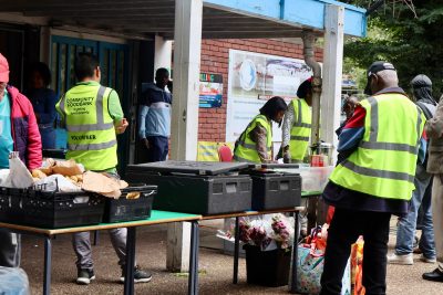 Several food bank volunteers organize crates of food for people who are waiting in line