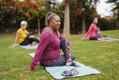 Women stretching on mats in a park