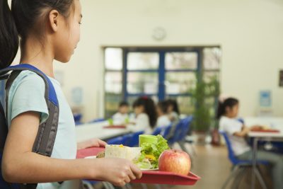 Student holding a tray of food in a school cafeteria