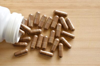 Supplement capsules spilling out of a white bottle