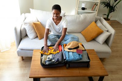 Woman sitting on a sofa packing clothes and getting ready for a vacation